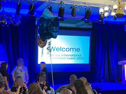 A stage lit up with blue lights and a screen with the word "Welcome" on it