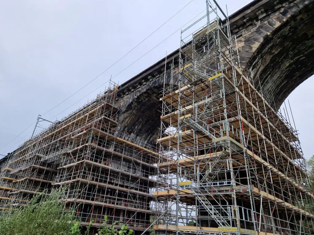 Looking up at brick built arches surrounded by scaffolding
