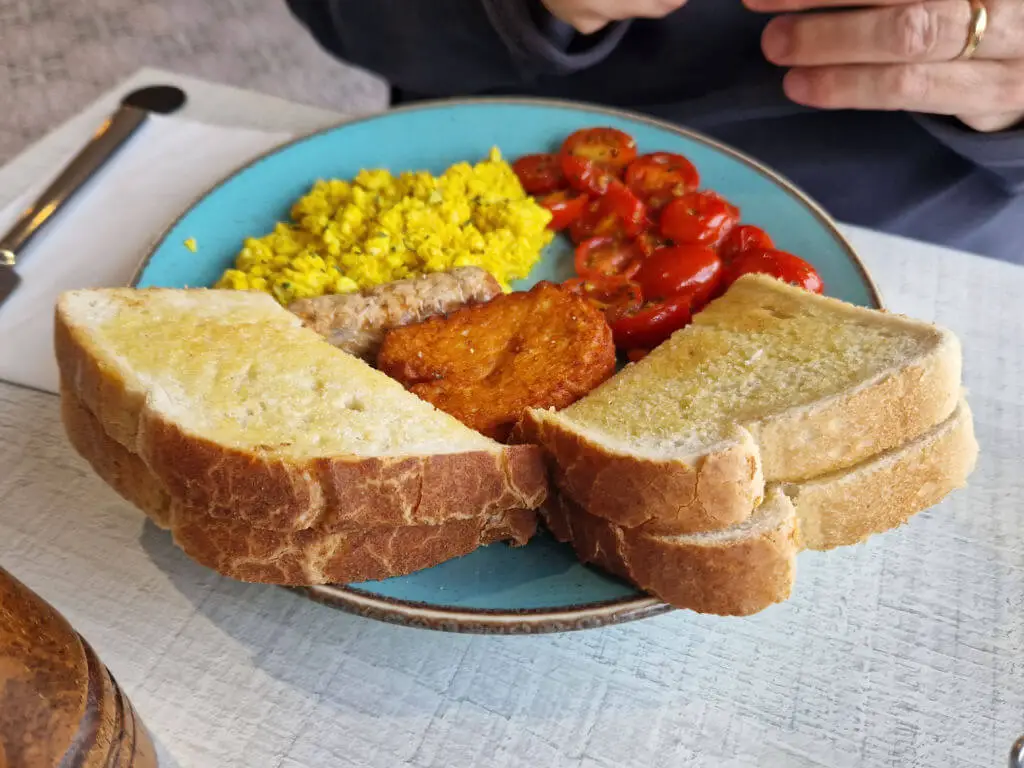 A round blue plate with toast, and a vegan cooked breakfast on it