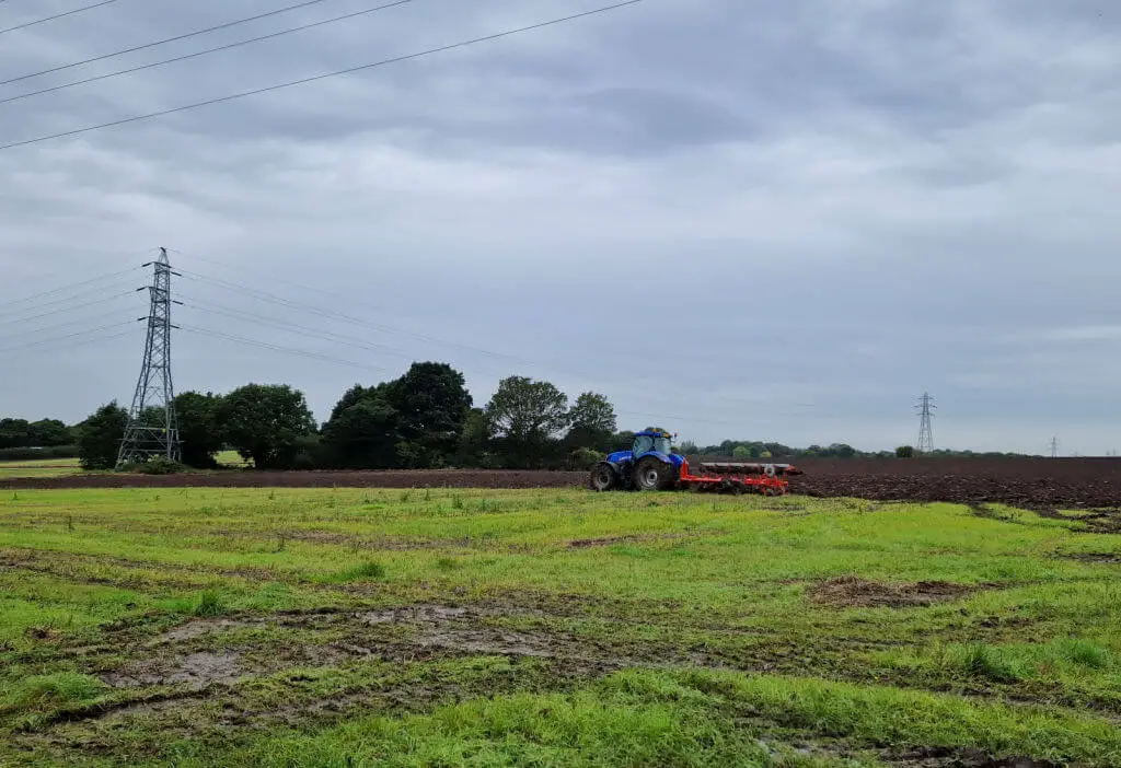 A tractor ploughing a field. The field looks very wet because of recent rain