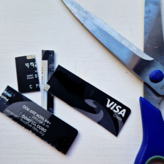 A chopped up credit card lying on a white table next to an open pair of scissors