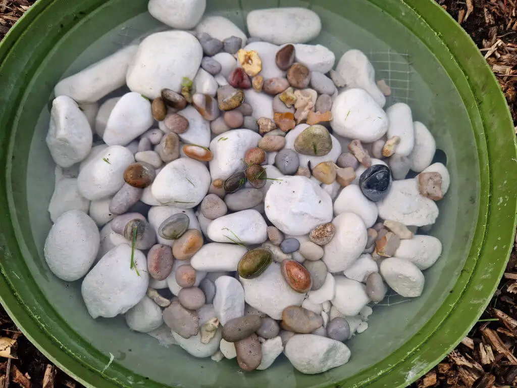 Coloured pebbles mixed with white cobbles in a green plastic pool