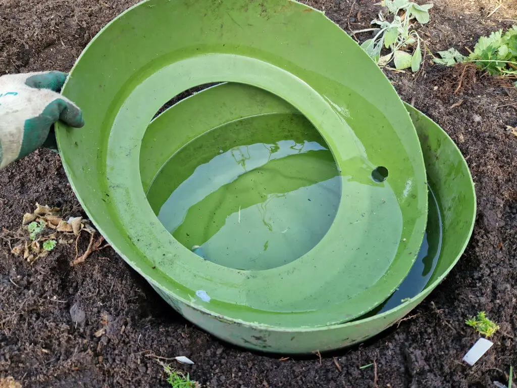 The top part of a water barrel cut to fit inside the bottom section being used as a small pond