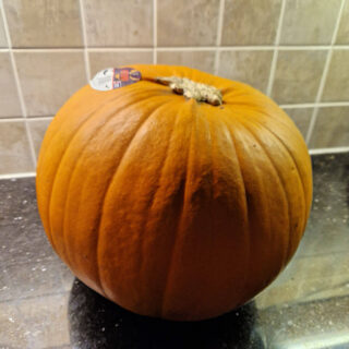 A large orange pumpkin sits on a kitchen worktop