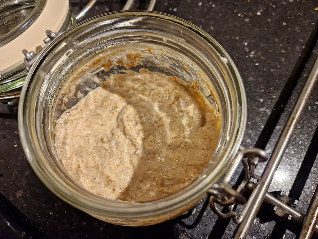 A brown mixture in a glass jar. The jar is sitting on a black granite worktop