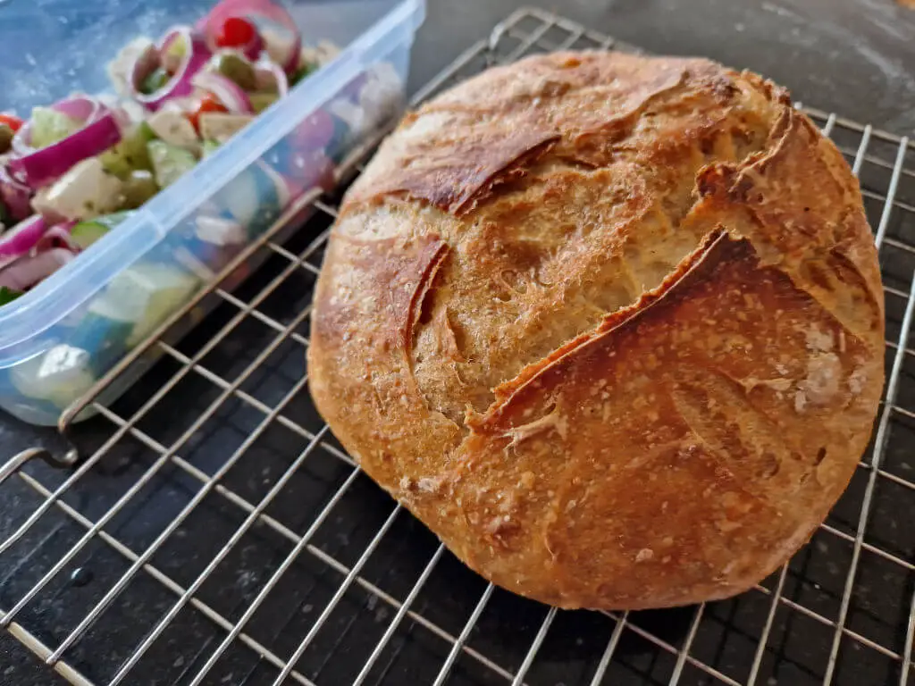 A round sourdough loaf on a cooling rack