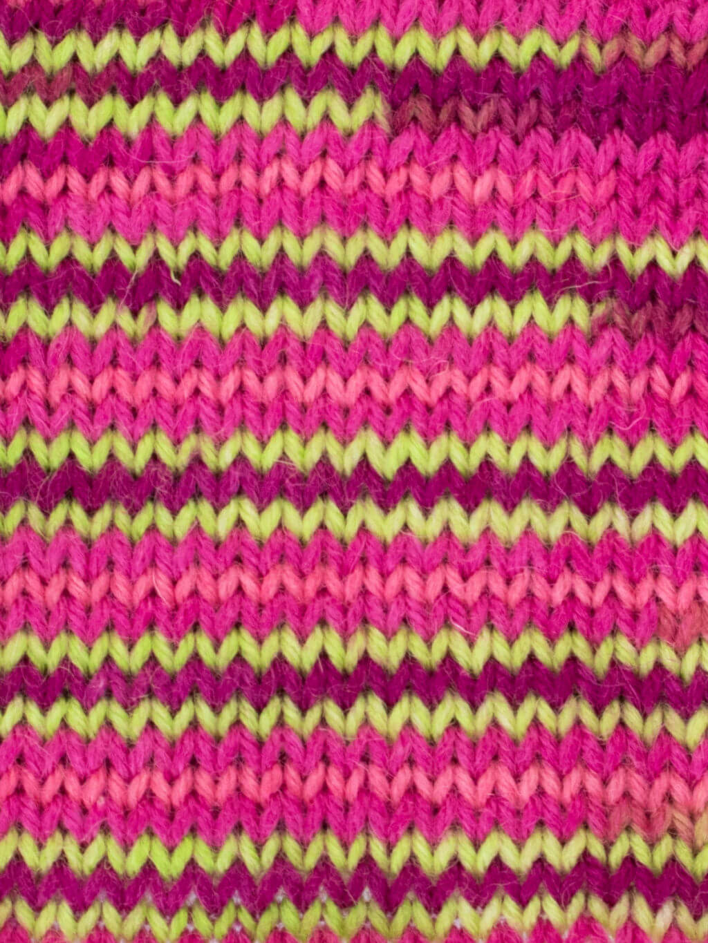 A striped knitting sample in shades of pink and neon green