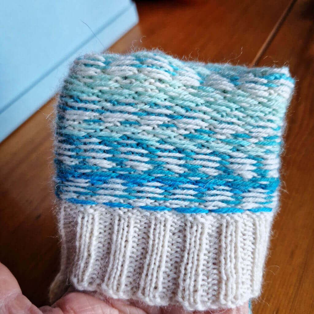 A close up of the floats at the back of a cream and blue striped colourwork sock