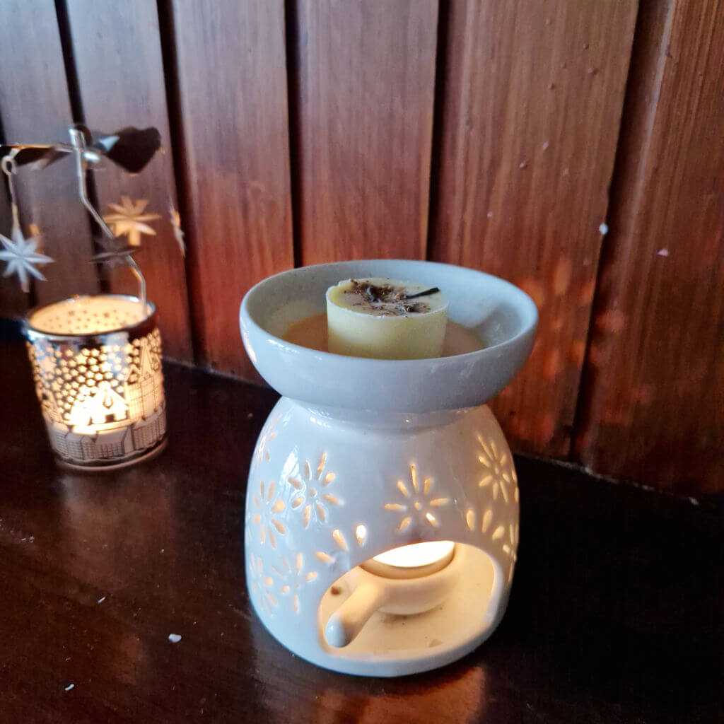 A wax melt with spices embedded in the wax sits in a wax melt burner