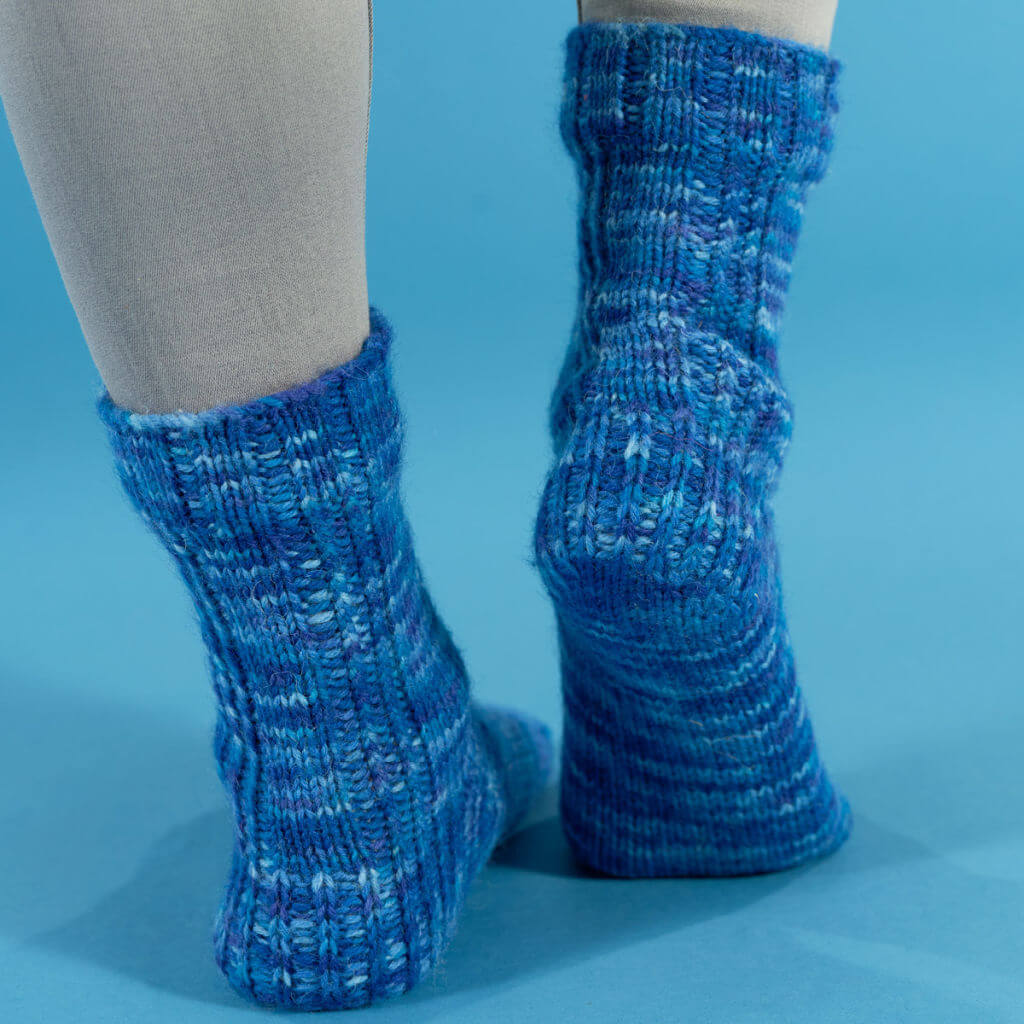 A pair of blue socks modelled on feet to show the back of the leg