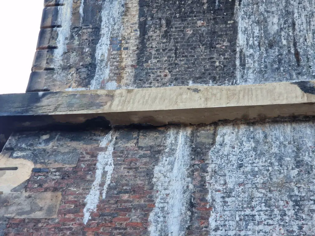 A close up of a repaired stone lintel previously damaged by lime dripping from the arched roof of a railway viaduct