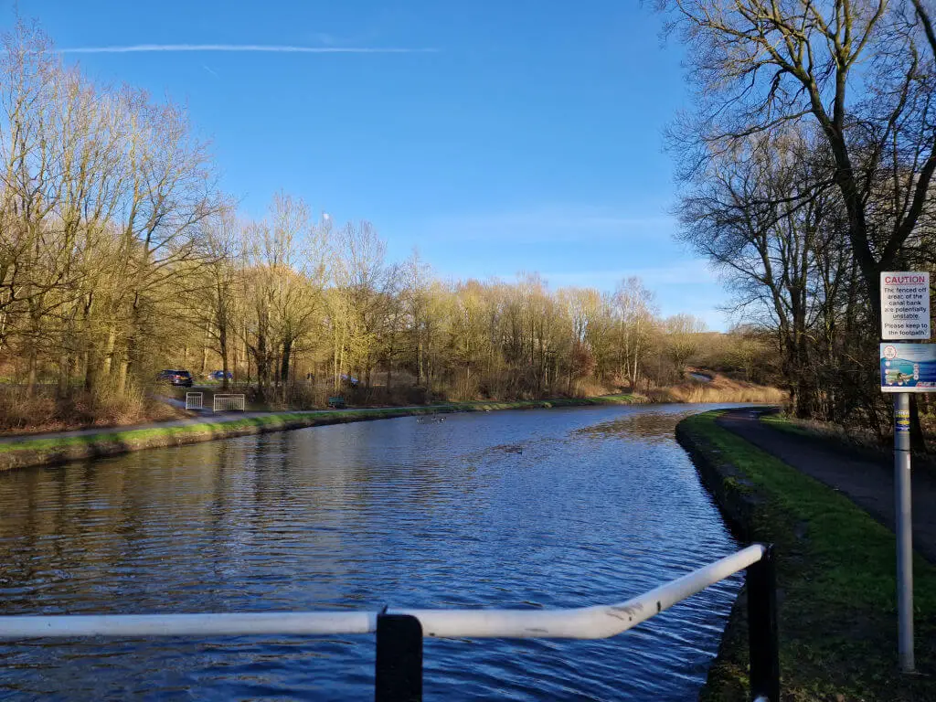 Looking across a canal on a winter's day. The sky is blue and mostly cloudless; the trees are bare