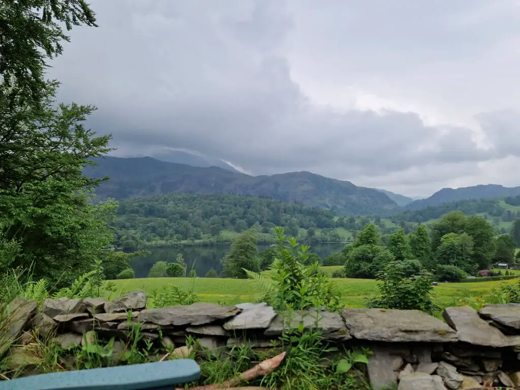 A closer view across a dry stone wall to the mountains beyond. The clouds above the mountains are very low.
