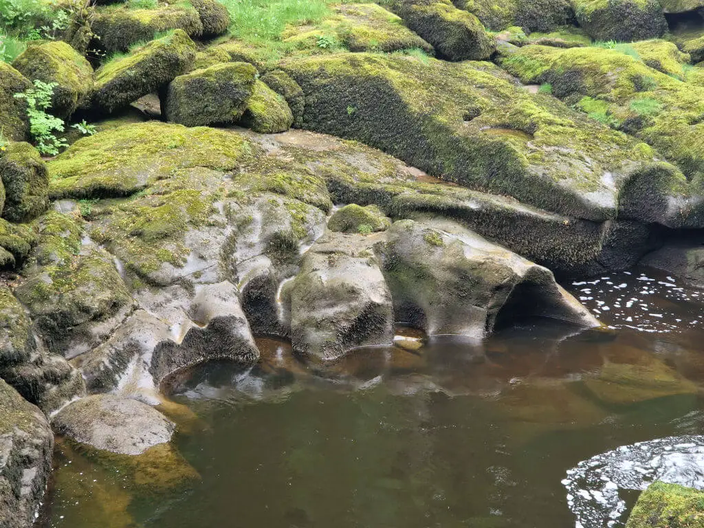 Worn millstone grit rocks in the water near The Strid, Yorkshire