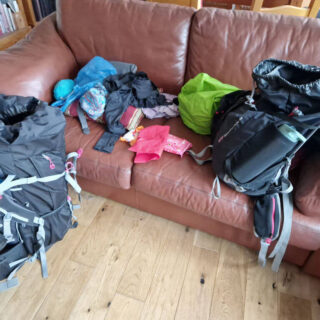 A brown leather sofa littered with the contents of two rucksacks