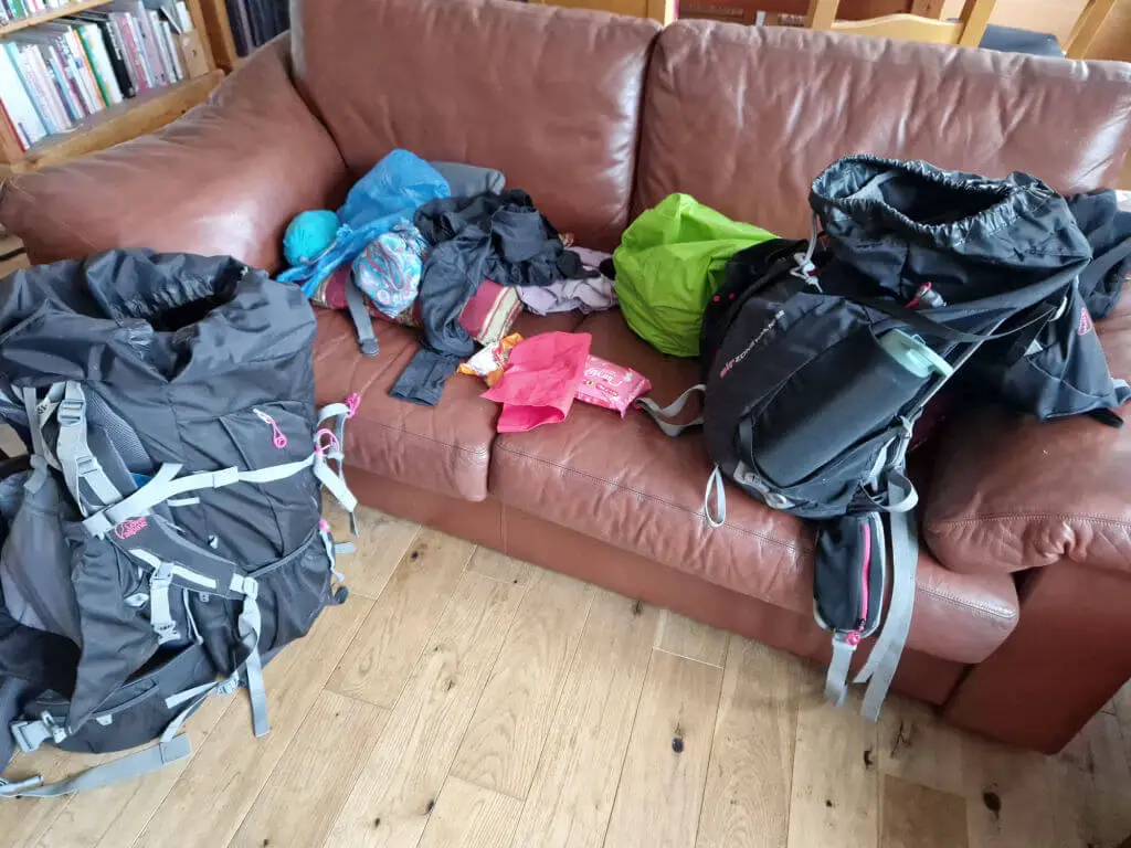 A brown leather sofa littered with the contents of two rucksacks