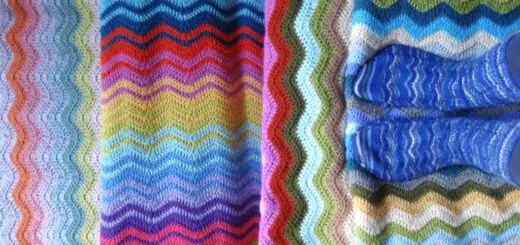 Four Attic24 Neat Ripple blankets arranged to show off the stripes, with Lucy standing on one of the blankets wearing a pair of Winwick Mum Neat Ripple socks in blue striped yarn