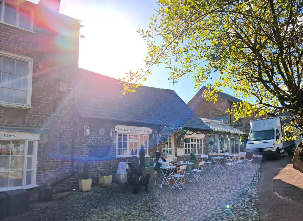 A single storey old-fashioned brick built tea room with multi-paned windows and seats outside