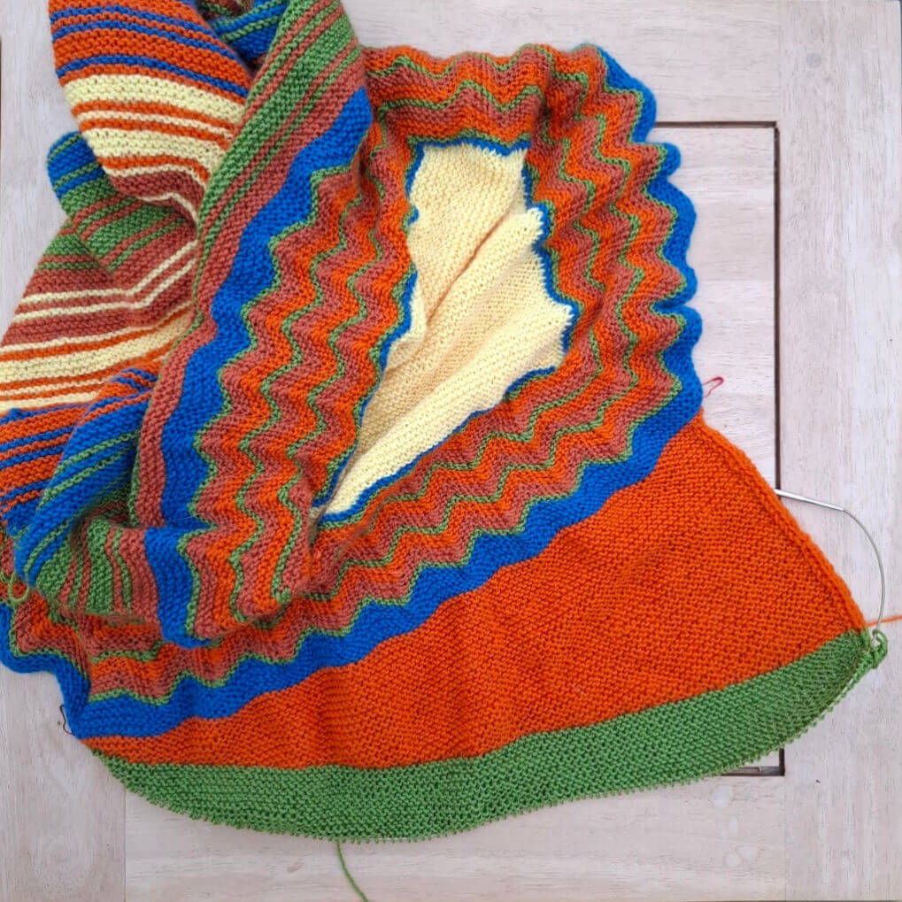 A partly-knitted shawl with large orange sections