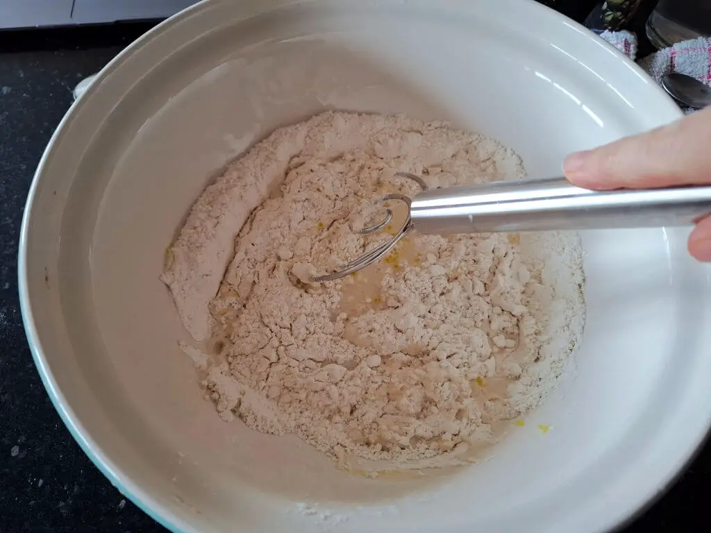 A dough mixture being mixed with a hand whisk