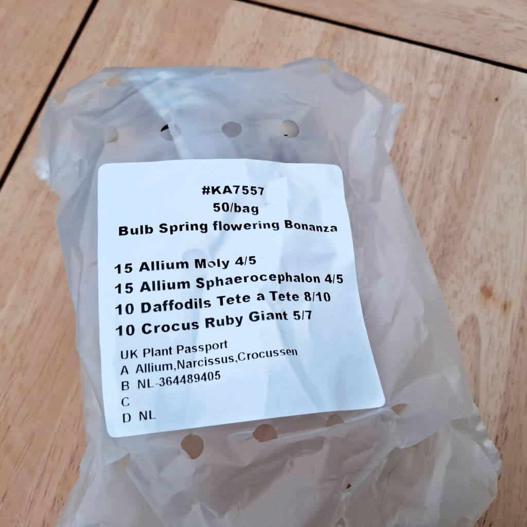 A plastic transit bag of flower bulbs lying on a wooden table