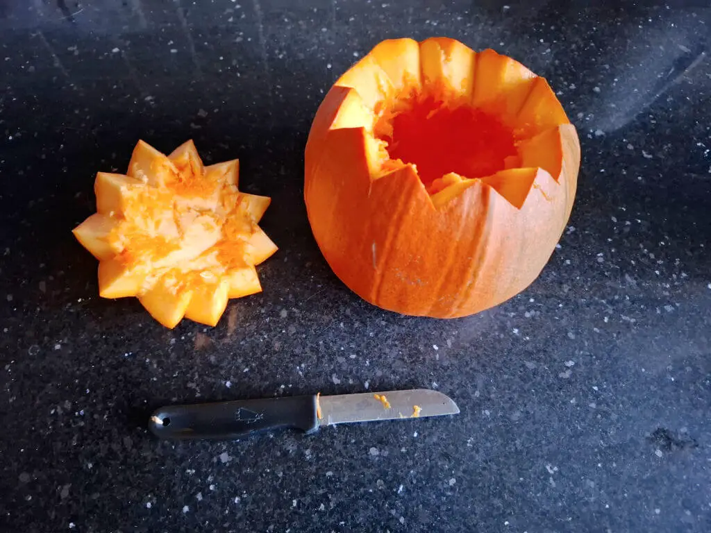 A small orange pumpkin with a serrated-edge lid next to it