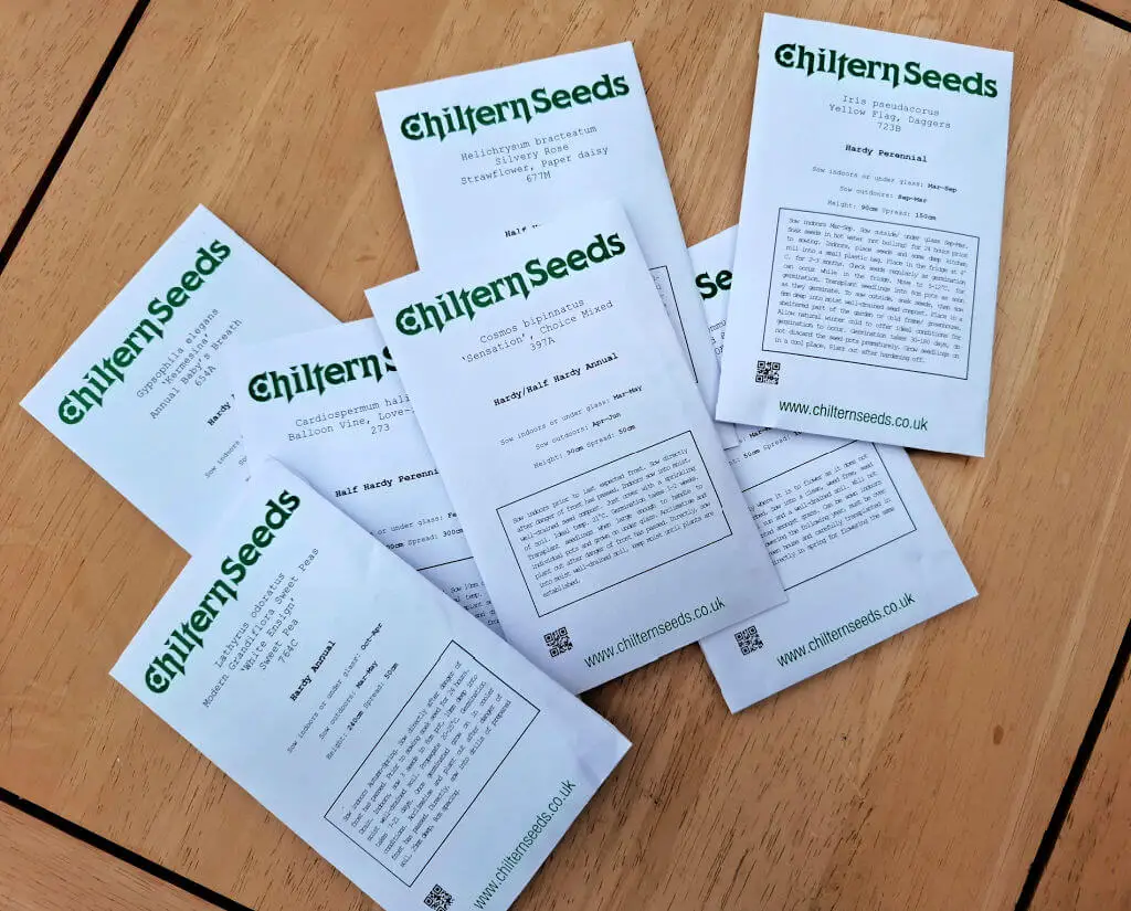 Seven white packets of seeds on a wooden table