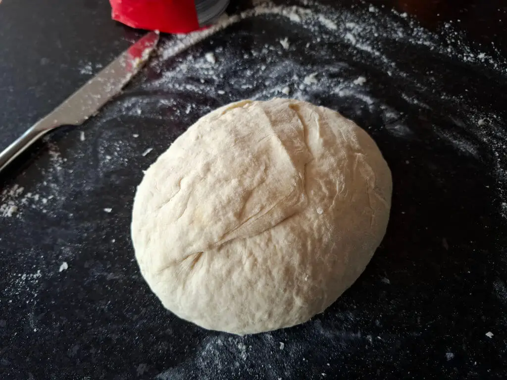 A round dough shape on a black working top