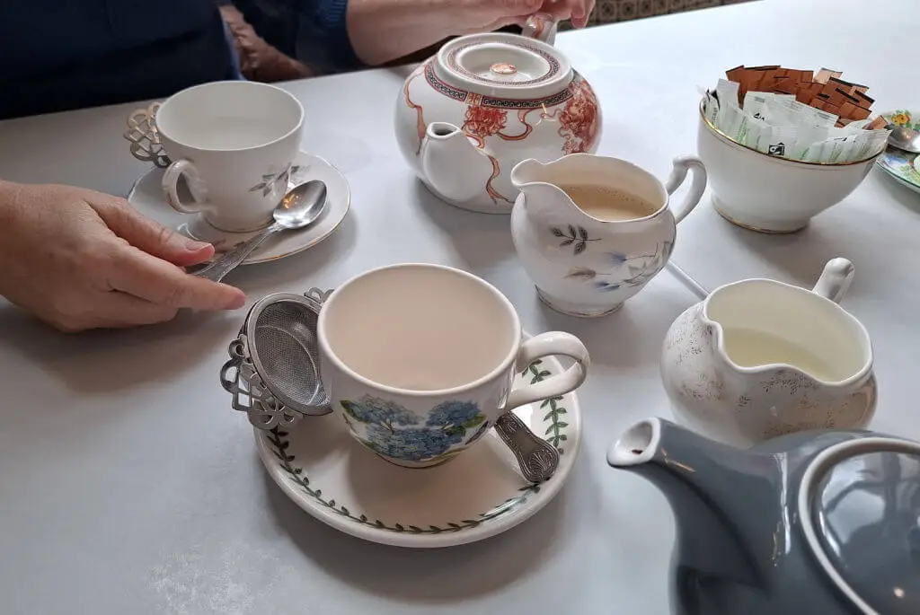Vintage china tea cups on matching saucers on a table covered with a white table cloth