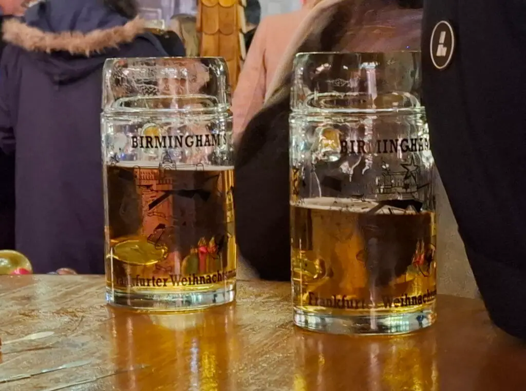 Two large stein glasses half-full of beer on a wooden table