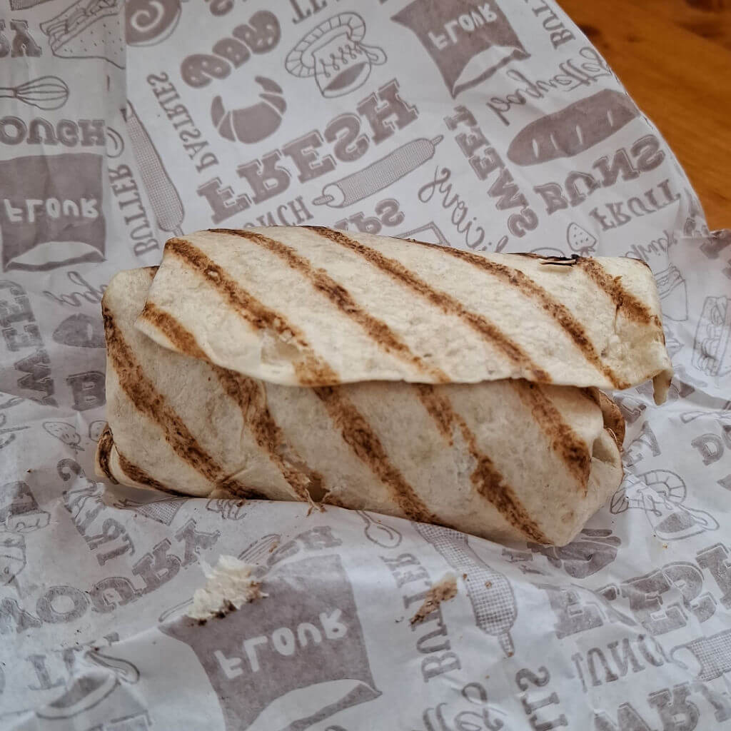 A large wrap sandwich on waxed paper