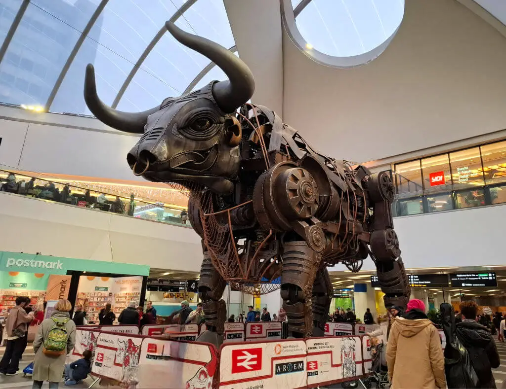 A giant metal bull sculpture in a railway station