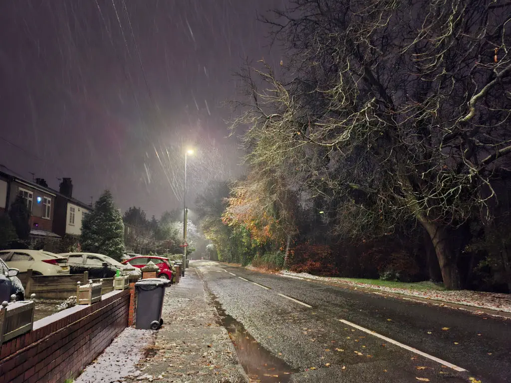 Snow falling on a street at night