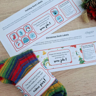 A striped multi-coloured pair of socks wrapped up with a decorated label. Another different label is also on the table to see