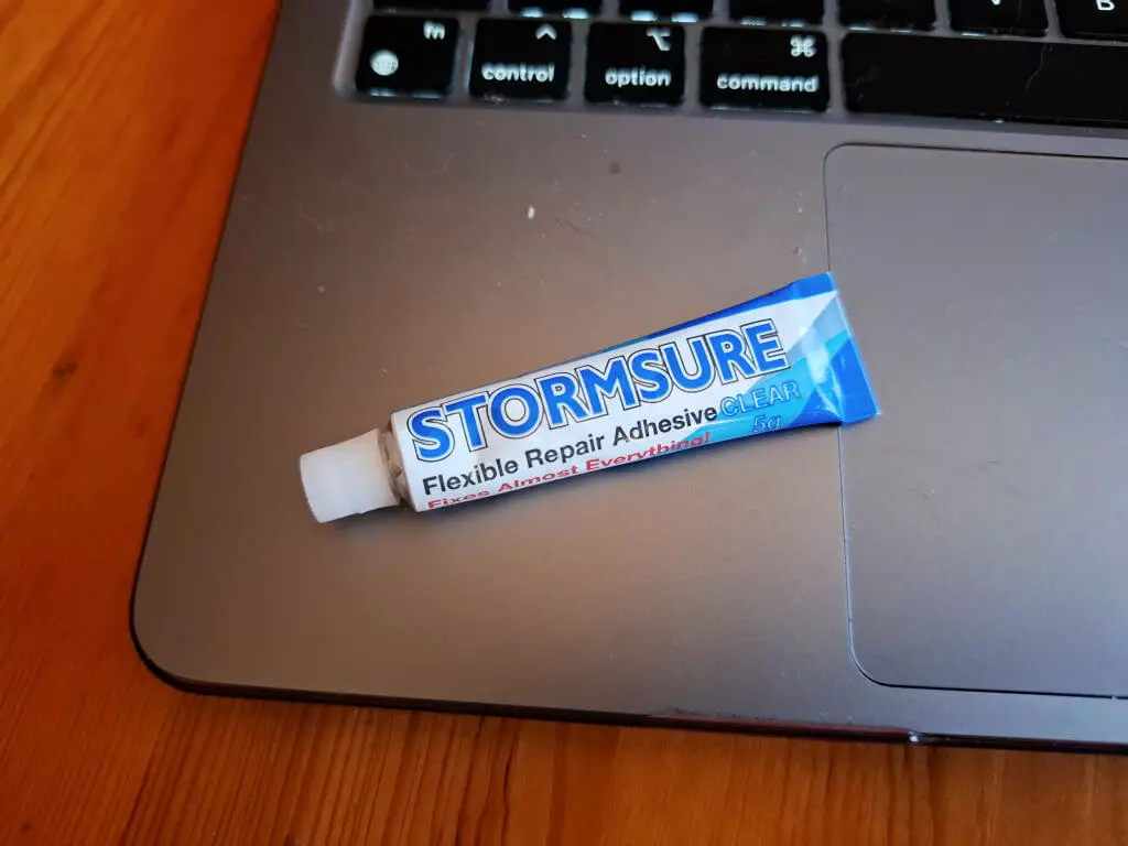 A small tube of flexible rubber glue sits on a laptop keyboard pad