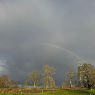 A partial rainbow across a grey stormy sky
