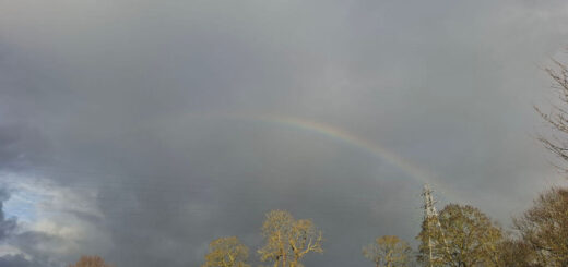 A partial rainbow across a grey stormy sky
