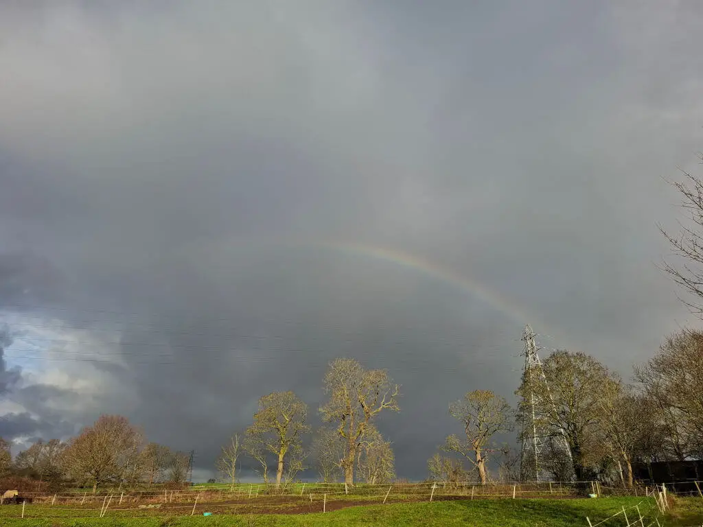 A partial rainbow across a grey stormy sky 