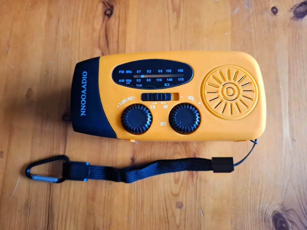 An orange and black wind up radio lying on a wooden table