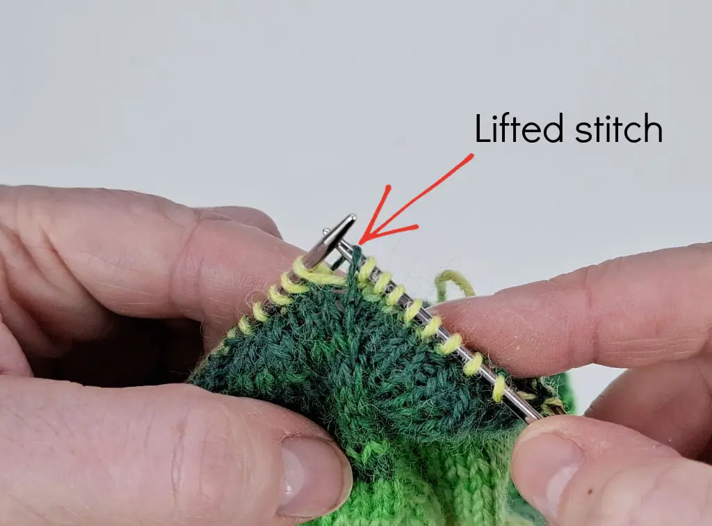 A close up of knitting on needles to explain an increase stitch