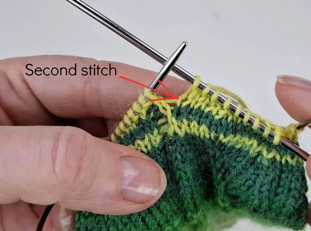 A close up of knitting on needles to explain an increase stitch