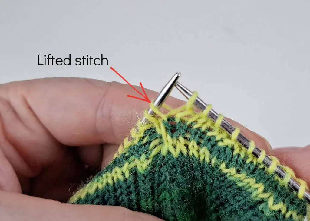 A close up of knitting on needles to explain an increase stitch