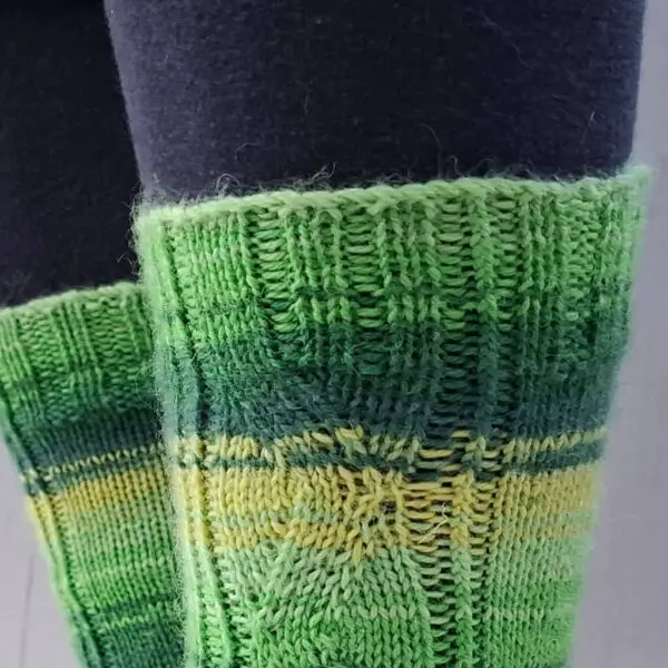 A close up of the cuff of a green and yellow striped sock