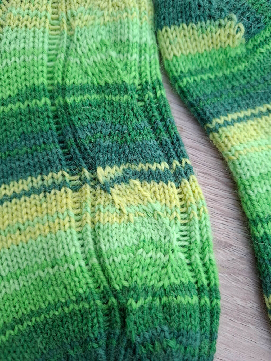 A close up of the pattern on the leg of a green and yellow striped sock