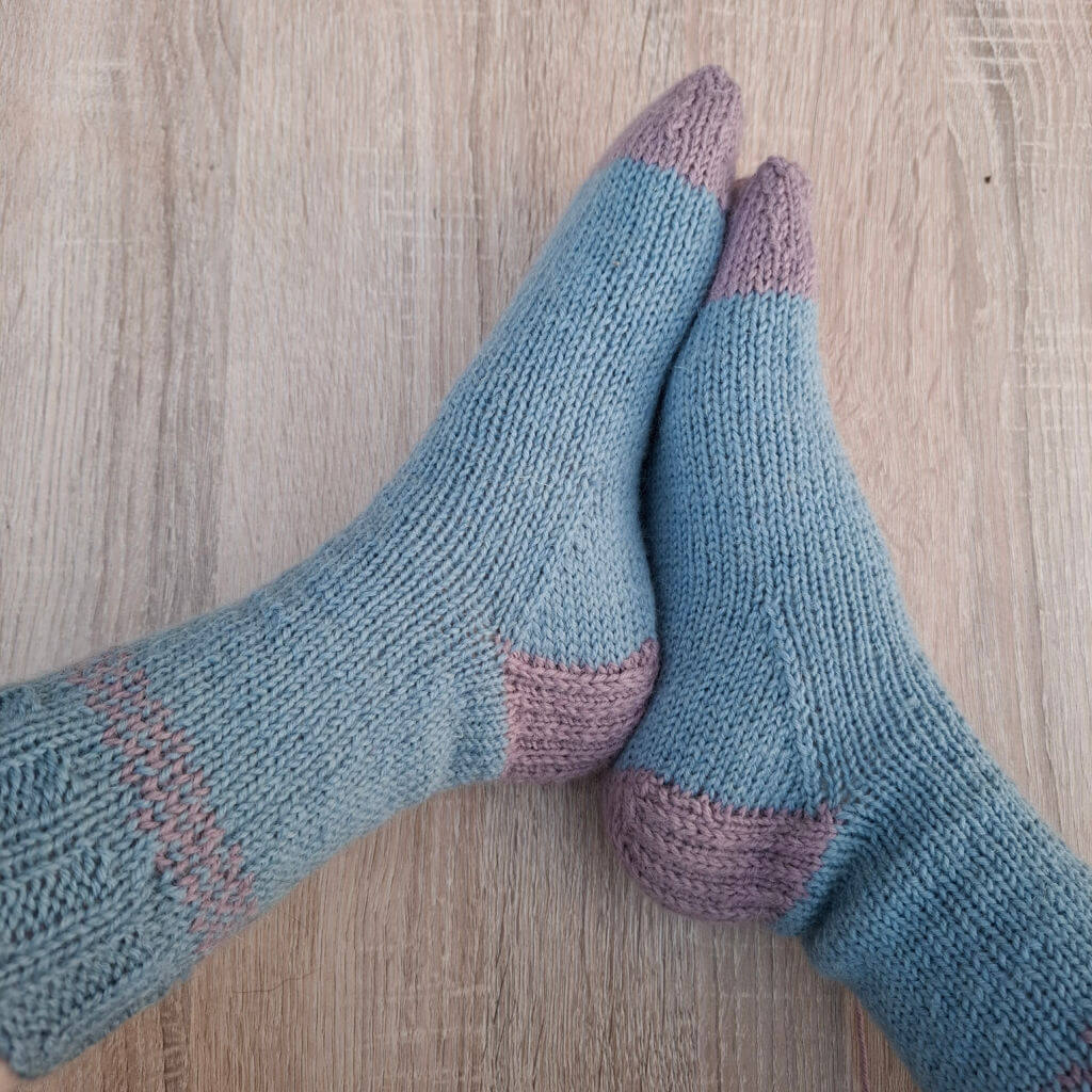 A pair of blue and pink socks modelled on feet
