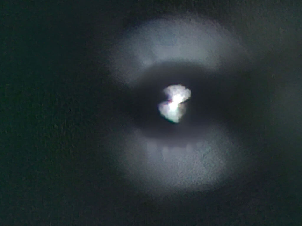 Blurred image of a glowing, heart-like shape surrounded by a circular halo on a dark background, conveying a mysterious, ethereal atmosphere.