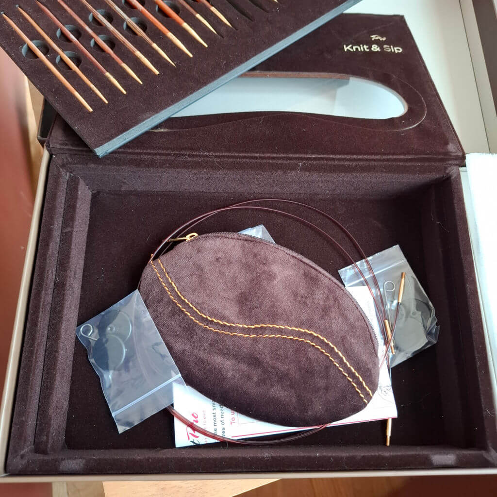 Open Knit & Sip box with wooden knitting needles neatly arranged. Inside, a brown suede pouch, plastic bags with small tools, and knitting wires | Winwick Mum KnitPro Knit & Sip Set Review