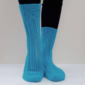 Two legs wearing bright teal, intricately knit knee-high socks with lace patterns over black leggings, set against a light background. Winwick Mum | Carousel Socks