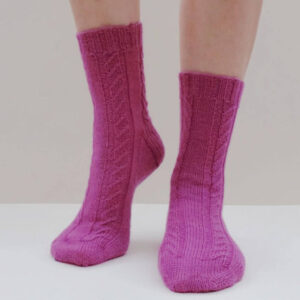 A pair of pink socks with a twisted stitch pattern modelled against a cream background. One heel is slightly raised.