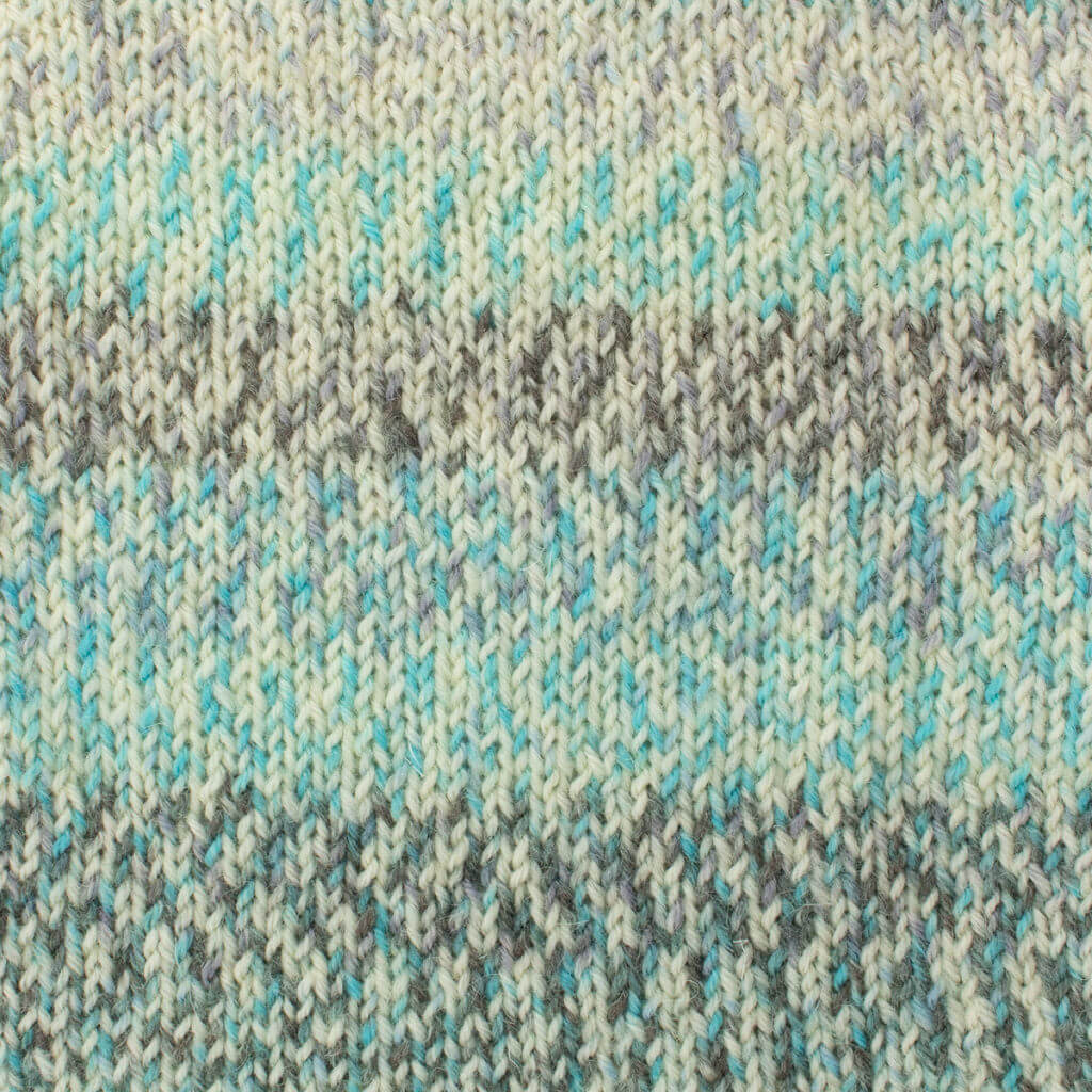 Close-up of West Yorkshire Spinners, Signature 4ply, Chalkhill Blue knitted fabric with a variegated pattern in soft mint, white, and gray tones. The texture is cozy and visually soothing.